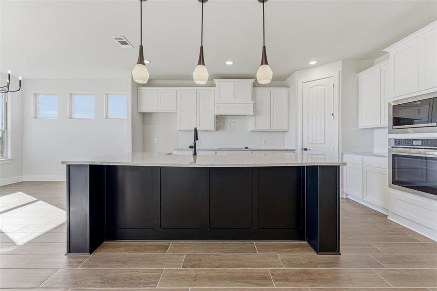Kitchen with white cabinetry, decorative light fixtures, stainless steel appliances, and recessed lighting