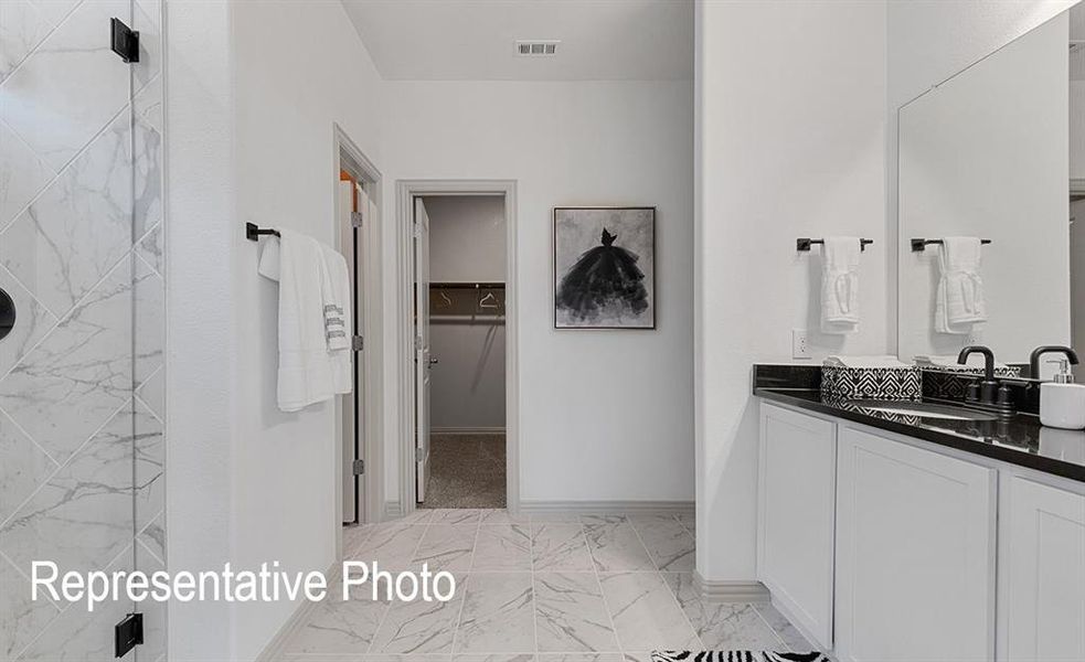 Modern bathroom featuring a dual vanity with white cabinetry, a dark countertop, and matte black fixtures