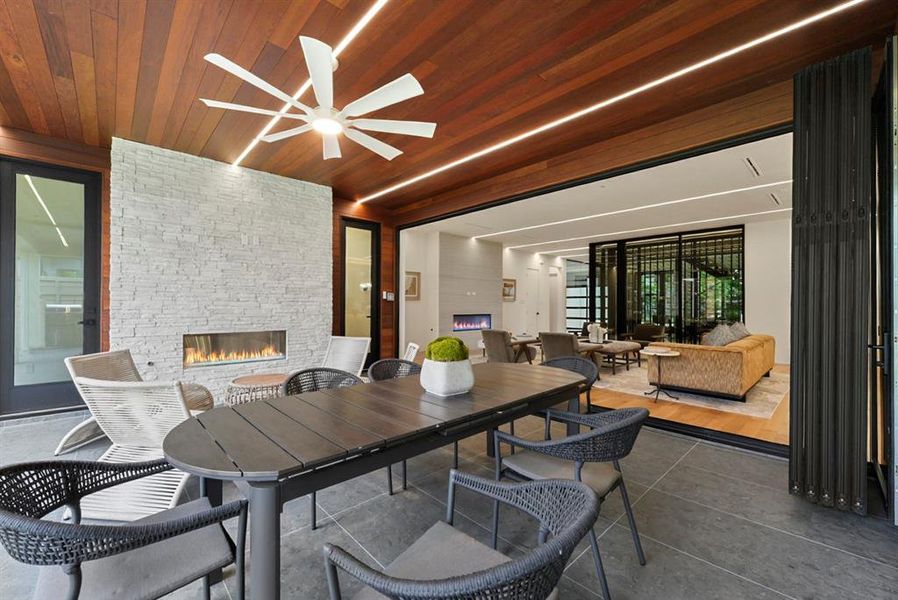 Outdoor covered patio with a wood-paneled ceiling, integrated linear lighting, and a modern ceiling fan