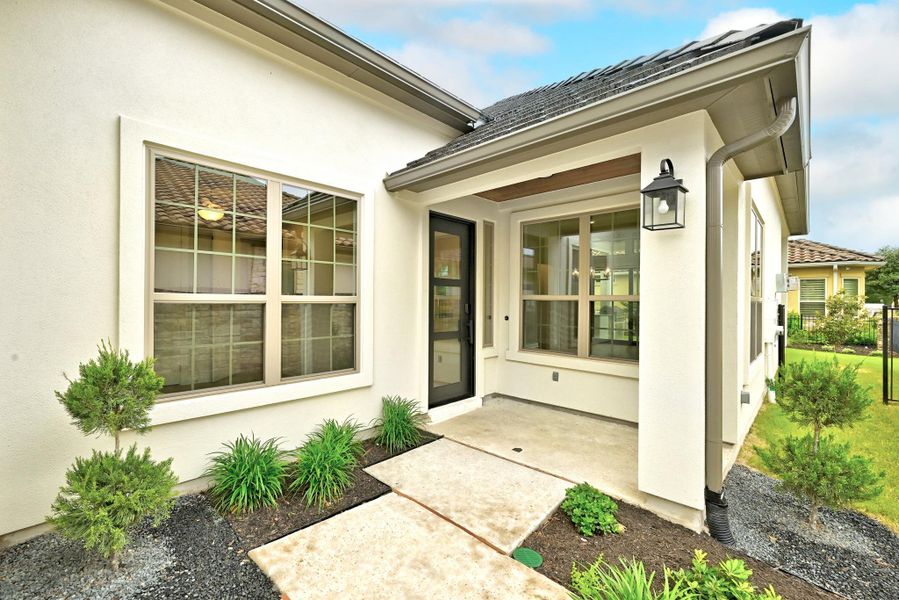 Stucco exterior featuring a covered entry, dark bronze outdoor lantern, and a dark bronze front door with glass panels