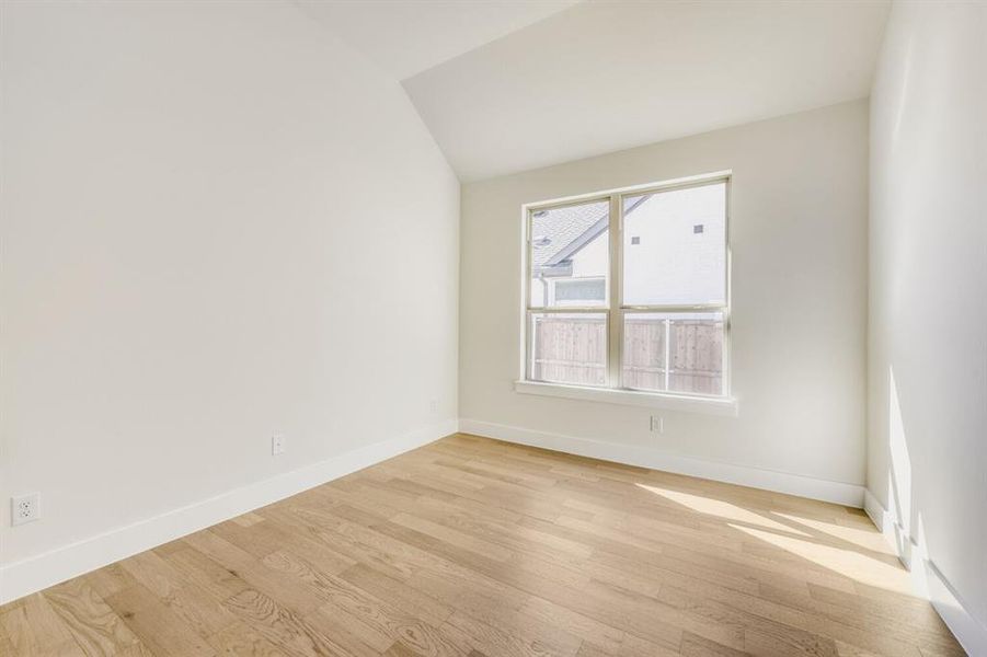 Empty room featuring light wood-style flooring and vaulted ceiling