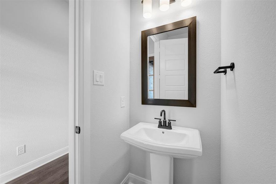 Bathroom featuring dark wood-type flooring and a textured wall Bathroom featuring dark wood-type flooring and a textured wall