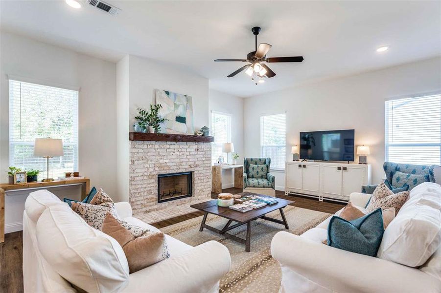 Living room with a fireplace, dark hardwood / wood-style floors, plenty of natural light, and ceiling fan