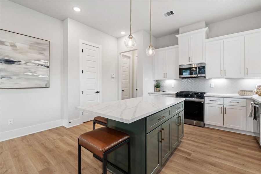 A statement island anchors the kitchen, combining contrasting cabinetry with ample workspace for both everyday use and casual gathering.
