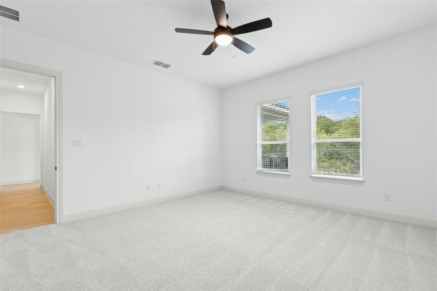 Unfurnished bedroom with light colored carpet and a ceiling fan Unfurnished bedroom with light colored carpet and a ceiling fan