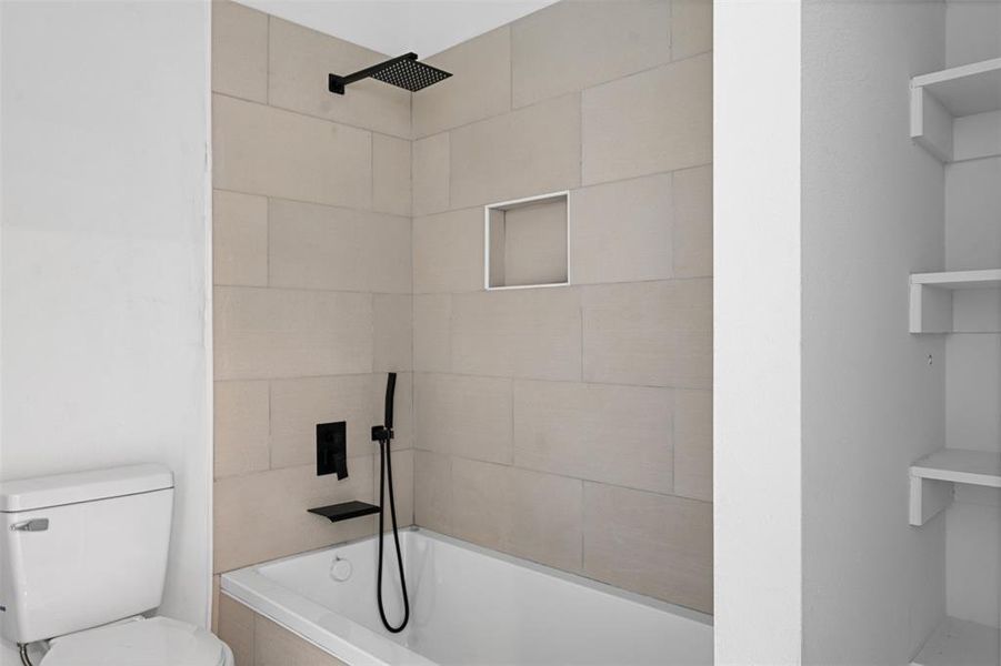 Bathroom with tiled shower / bath combo and toilet