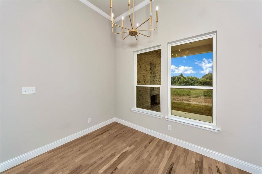 Unfurnished dining area featuring wood-type flooring, ornamental molding, and an inviting chandelier