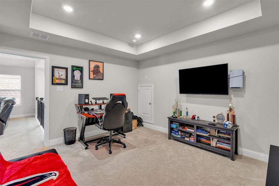 Carpeted room with a tray ceiling and recessed lighting, featuring light gray walls and white trim