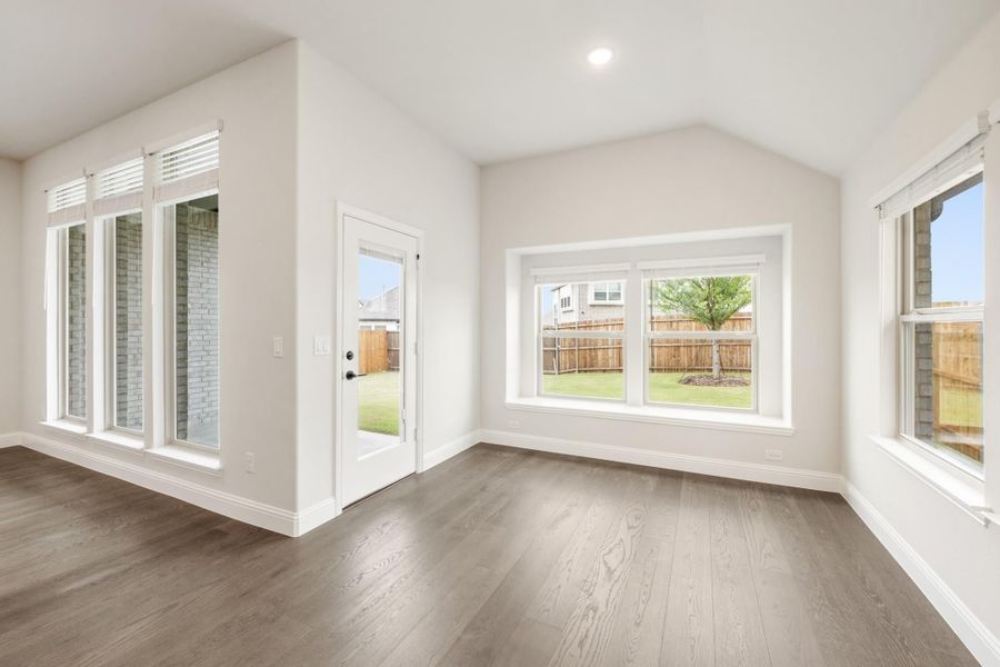 Empty room with vaulted ceiling, hardwood floors, and back door leading to fenced yard Empty room with vaulted ceiling, hardwood floors, and back door leading to fenced yard