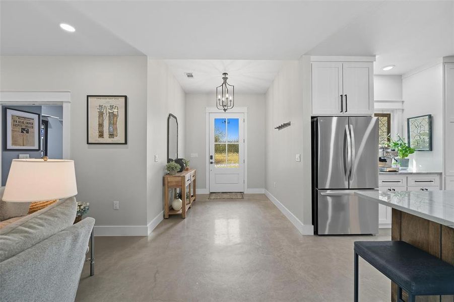 Foyer entrance featuring recessed lighting, concrete floors, and a chandelier Foyer entrance featuring recessed lighting, concrete floors, and a chandelier