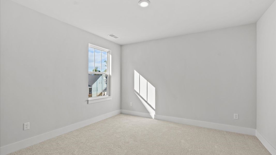 Elegant bedroom retreat featuring soft carpet and oversized windows that create a bright, welcoming space