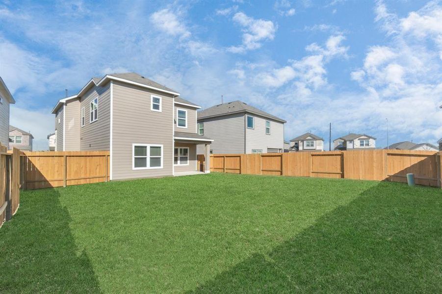 A broader view of the backyard reveals the full scope of the outdoor space and the attractive exterior of the home. The expansive lawn is ideal for hosting gatherings, while the well-maintained fence ensures privacy. This backyard is a blank canvas, ready for you to create your dream outdoor living area or simply enjoy the open space.