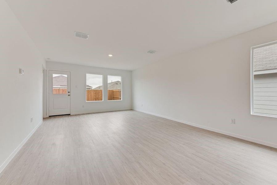 Empty room with light wood-style floors, visible vents, and baseboards