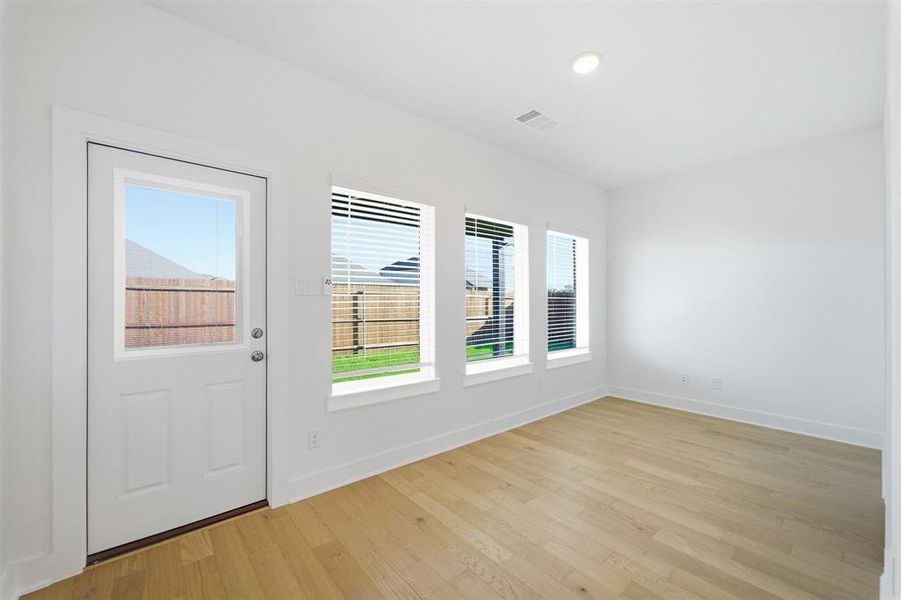 Bright interior space featuring light wood-finish flooring, white walls, and a recessed ceiling light Bright interior space featuring light wood-finish flooring, white walls, and a recessed ceiling light