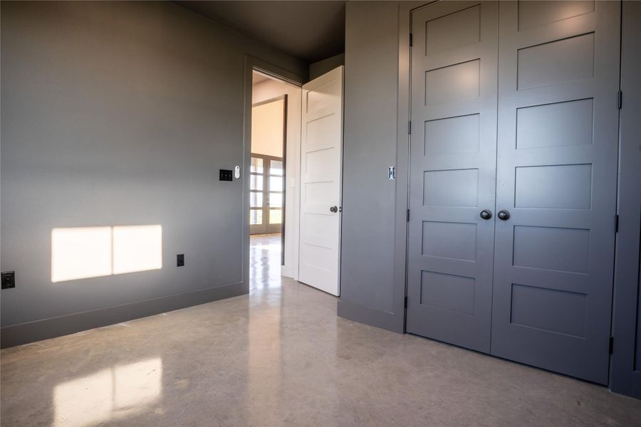 Unfurnished bedroom with finished concrete flooring and a closet