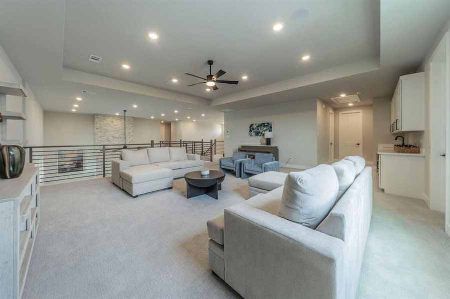 Living area with light colored carpet, a tray ceiling, ceiling fan, and recessed lighting Living area with light colored carpet, a tray ceiling, ceiling fan, and recessed lighting