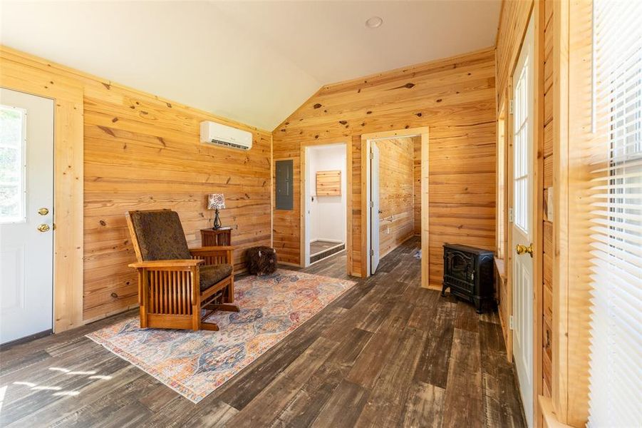 Vaulted ceiling sunroom featuring wood-finish flooring, natural wood plank walls, and a mini-split HVAC unit