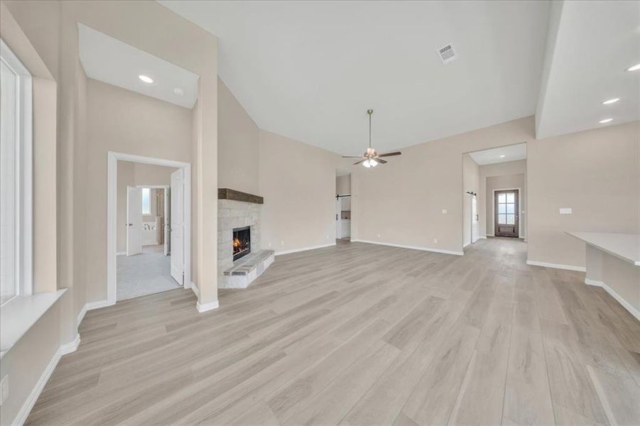 Unfurnished living room featuring light wood-type flooring, ceiling fan, a fireplace, and recessed lighting Unfurnished living room featuring light wood-type flooring, ceiling fan, a fireplace, and recessed lighting