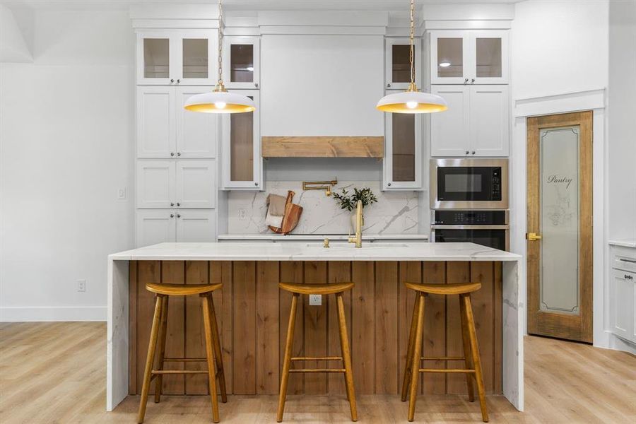 Kitchen with decorative light fixtures, stainless steel appliances, and light wood-type flooring