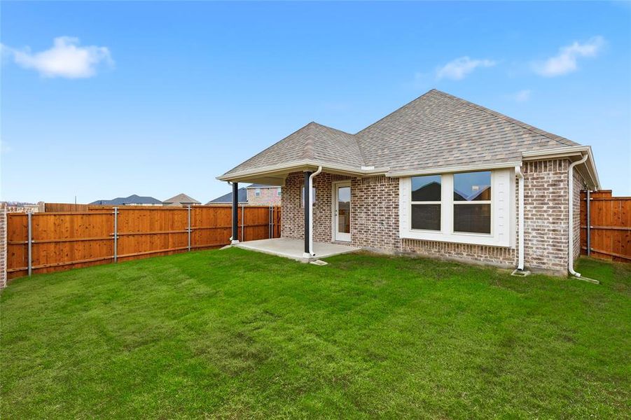 Rear view of property featuring brick siding, a patio, a shingled roof, and a fenced backyard