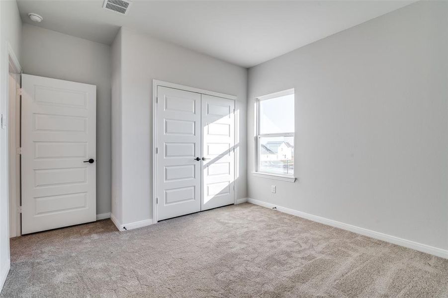 Unfurnished bedroom featuring light carpet and a closet