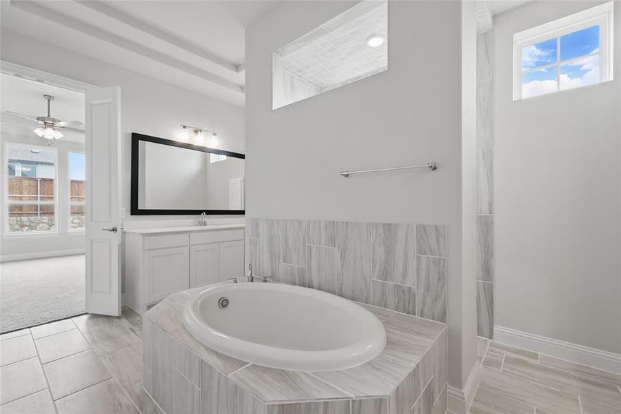 Full bath featuring a garden tub, a ceiling fan, vanity, and baseboards Full bath featuring a garden tub, a ceiling fan, vanity, and baseboards