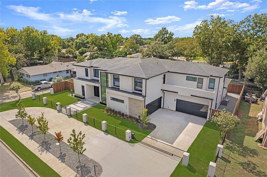 View of front facade featuring stucco siding, an attached garage, driveway, a fenced front yard, and view of wooded area