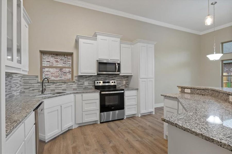 Kitchen featuring white cabinets, light hardwood / wood-style flooring, appliances with stainless steel finishes, and decorative backsplash