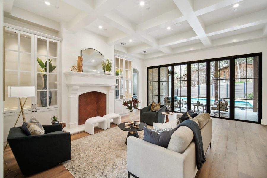 Living area featuring beamed ceiling, a fireplace with raised hearth, and coffered ceiling