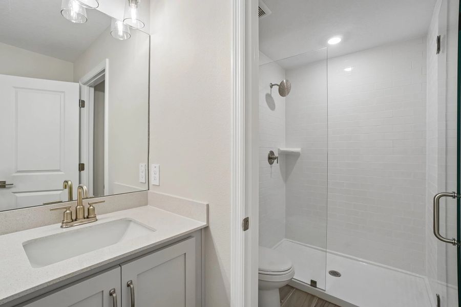 Primary bathroom featuring a frameless walk-in shower