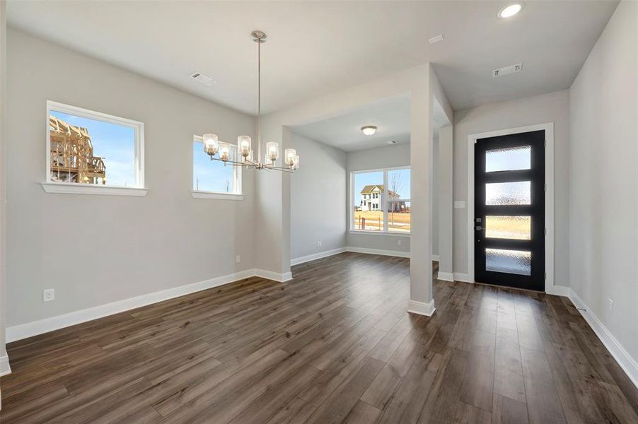 Foyer entrance with dark wood-style floors, a chandelier, and healthy amount of natural light