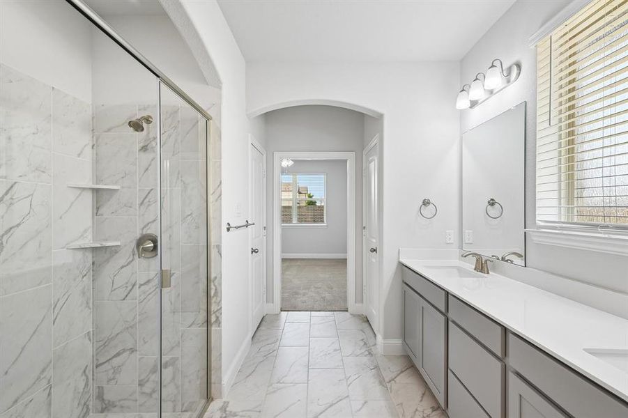 Contemporary bathroom featuring a spacious walk-in shower with glass enclosure and integrated shelving, dual vanity with undermount sinks and light-toned countertops, and marble-look tile flooring Contemporary bathroom featuring a spacious walk-in shower with glass enclosure and integrated shelving, dual vanity with undermount sinks and light-toned countertops, and marble-look tile flooring