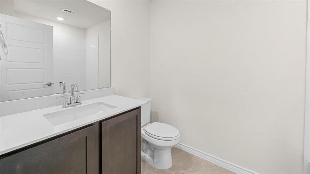 Bathroom vanity featuring a white countertop with integrated sink, chrome faucet, and dark wood-finish cabinetry