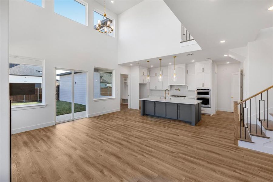 Unfurnished living room featuring sink, light hardwood / wood-style floors, a wealth of natural light, and a chandelier