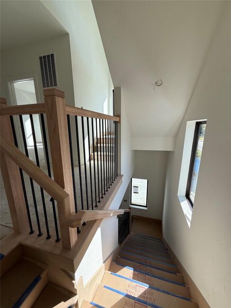 The stairway features natural wood handrails with sleek black iron spindles, continuing the home’s balance of warmth and modern contrast. Oversized windows illuminate the stairs with natural light, leading to the upper-level living areas and bedrooms with a sense of openness and architectural flow. The stairway features natural wood handrails with sleek black iron spindles, continuing the home’s balance of warmth and modern contrast. Oversized windows illuminate the stairs with natural light, leading to the upper-level living areas and bedrooms with a sense of openness and architectural flow.