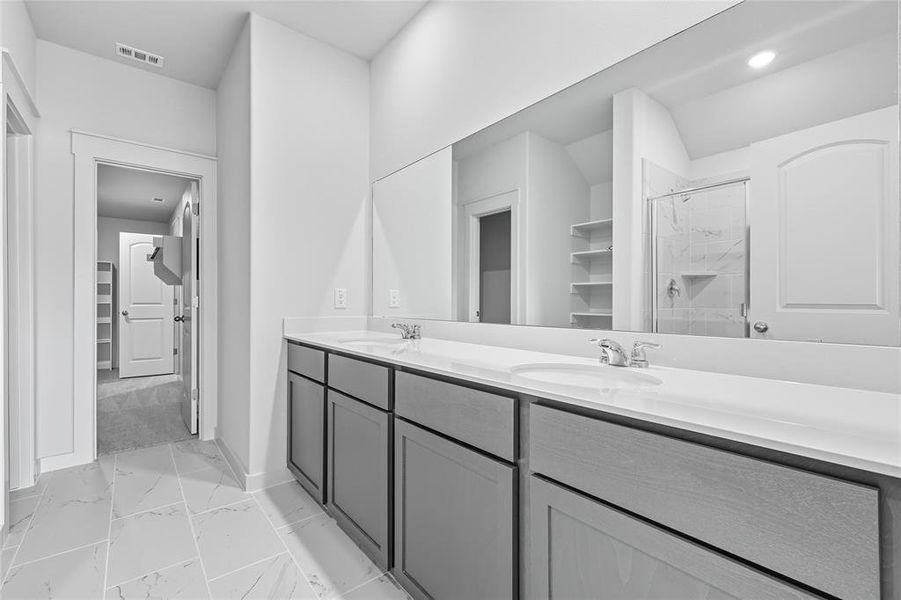 Bathroom with a marble finish shower, double vanity, and light marble finish floors