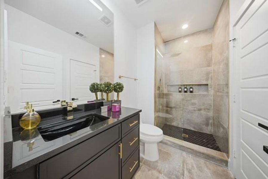 Bathroom featuring a black vanity with gold-tone hardware, a black vessel sink, and a black countertop