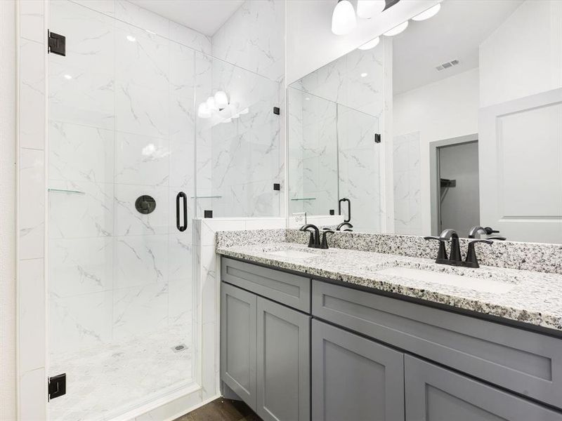 Bathroom featuring double vanity and a marble finish shower Bathroom featuring double vanity and a marble finish shower