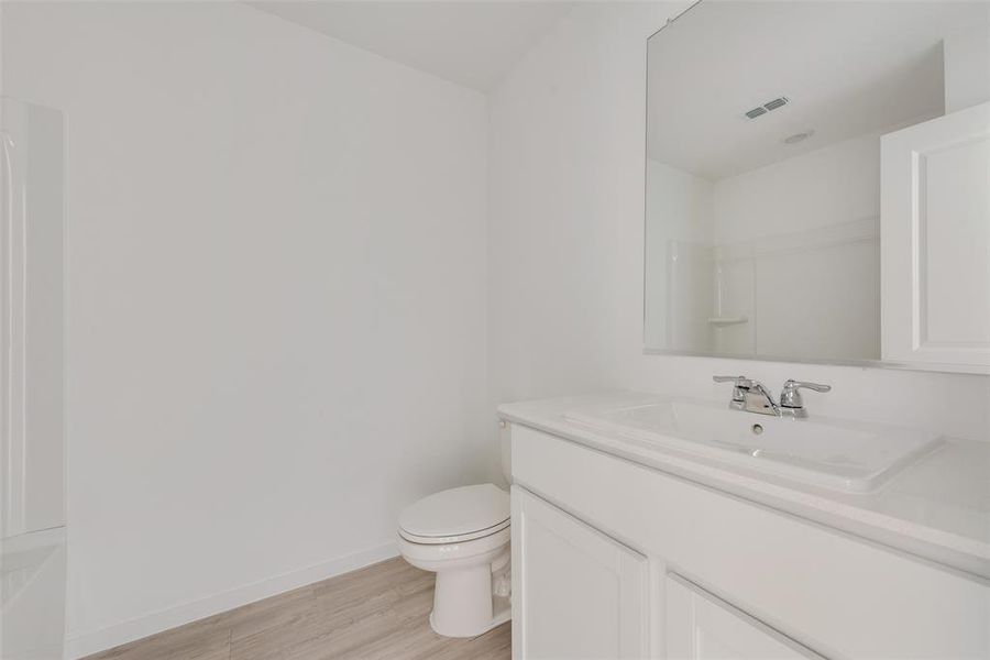 Bathroom with toilet, vanity, wood-type flooring, and walk in shower