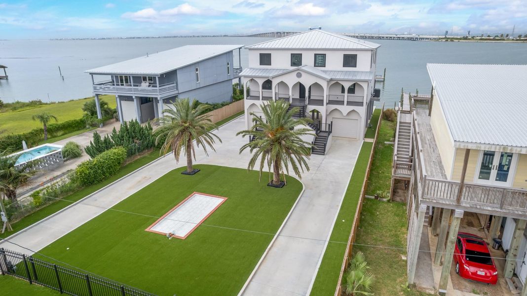 This aerial perspective reveals the impressive scale of the property. The home sits behind a broad private drive with mature palms, a large fenced yard, and generous outdoor space. Buyers have room to welcome guests and personalize the grounds around their lifestyle. This aerial perspective reveals the impressive scale of the property. The home sits behind a broad private drive with mature palms, a large fenced yard, and generous outdoor space. Buyers have room to welcome guests and personalize the grounds around their lifestyle.