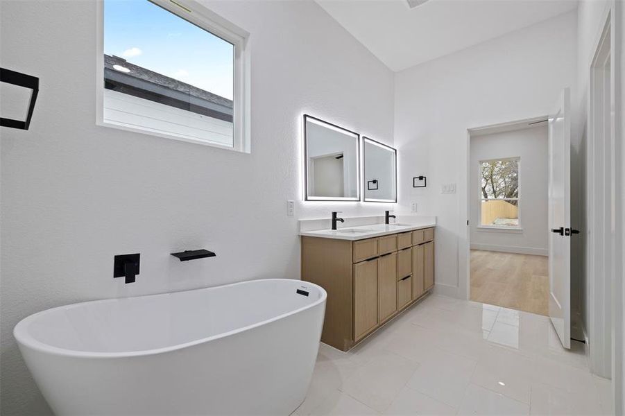 Bathroom featuring a freestanding tub, double vanity, and light tile patterned flooring