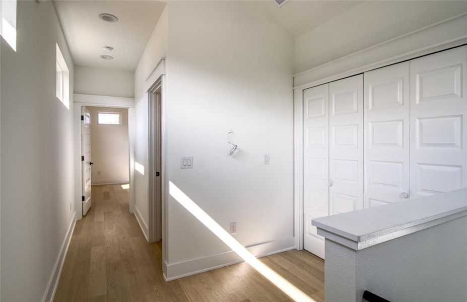 Corridor featuring light wood-style floors and baseboards Corridor featuring light wood-style floors and baseboards