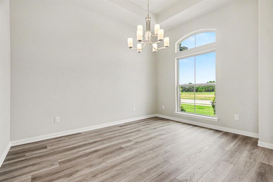 Bright interior space featuring a large arched window, vaulted ceiling, and wood-finish flooring Bright interior space featuring a large arched window, vaulted ceiling, and wood-finish flooring