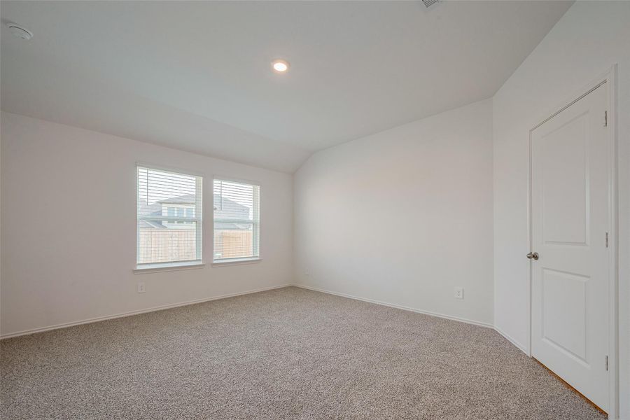 A generously sized primary suite features soft carpeting, a gentle ceiling slope for added dimension, and expansive windows that bring in plenty of natural light. A generously sized primary suite features soft carpeting, a gentle ceiling slope for added dimension, and expansive windows that bring in plenty of natural light.