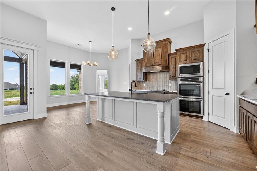 Kitchen with an island with sink, stainless steel appliances, a chandelier, and tasteful backsplash