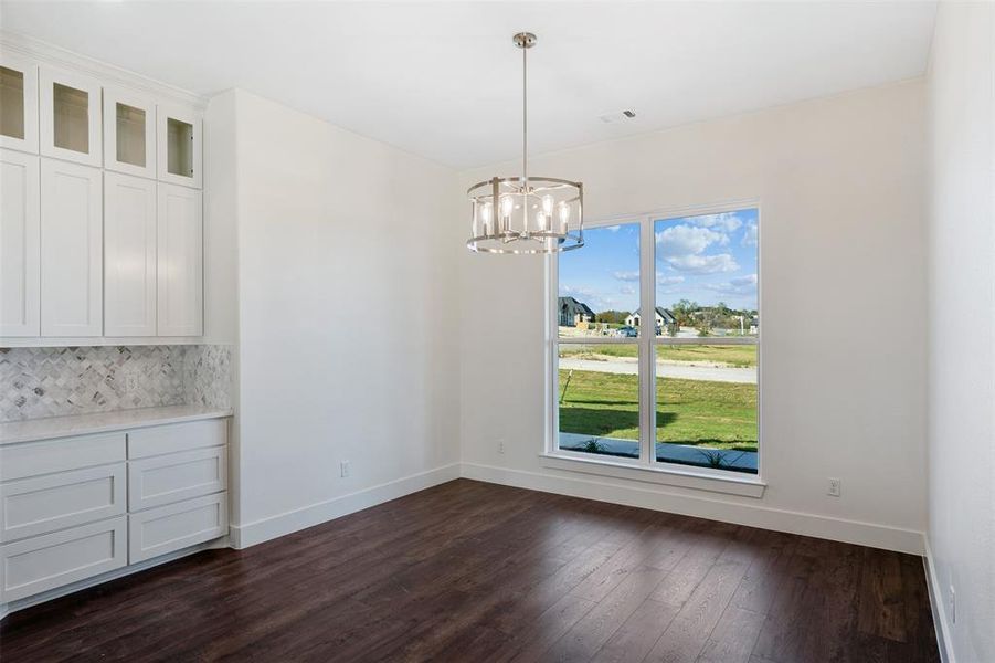 Unfurnished dining area with dark wood-type flooring and a notable chandelier