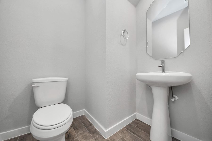 This half bathroom features a stylish pedestal sink, modern hardware, and bright recessed lighting, creating a sleek and inviting space. Sample photo of completed home with similar floor plan. Actual colors and selections may vary.