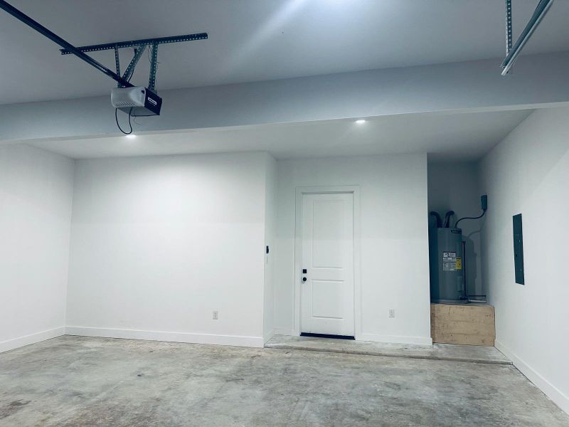 Garage with water heater, electric panel, and a garage door opener Garage with water heater, electric panel, and a garage door opener