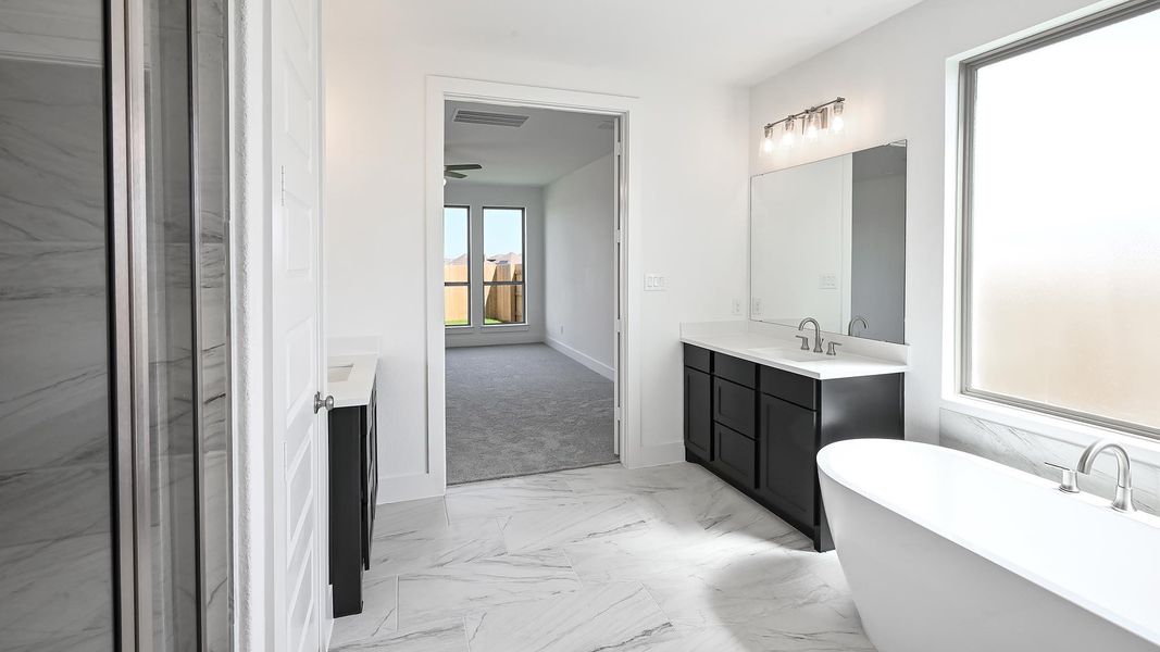 Full bathroom featuring marble look tile flooring, vanity, and a soaking tub