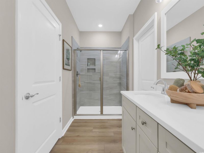 Full bath featuring a stall shower, vanity, light wood-style flooring, and recessed lighting